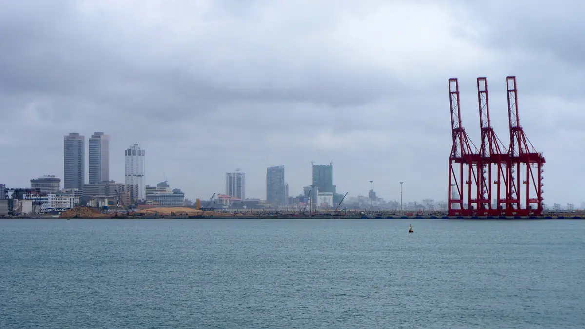 Gantry cranes at the Port of Colombo, with tower cranes visible on the city skyline.